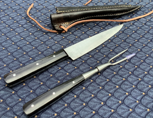 Medieval knife and fork set with black horn handles, featuring a sharp steel blade and pricker, accompanied by a black leather sheath with laces.