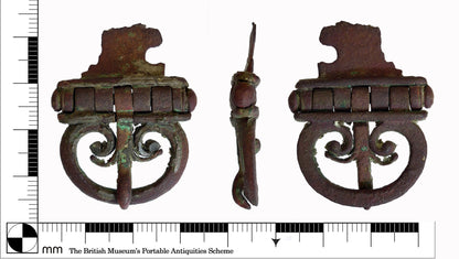 Roman buckle artifact from the British Museum's Portable Antiquities Scheme. Displays a hinged design with intricate scrollwork, indicative of historical belt fittings.